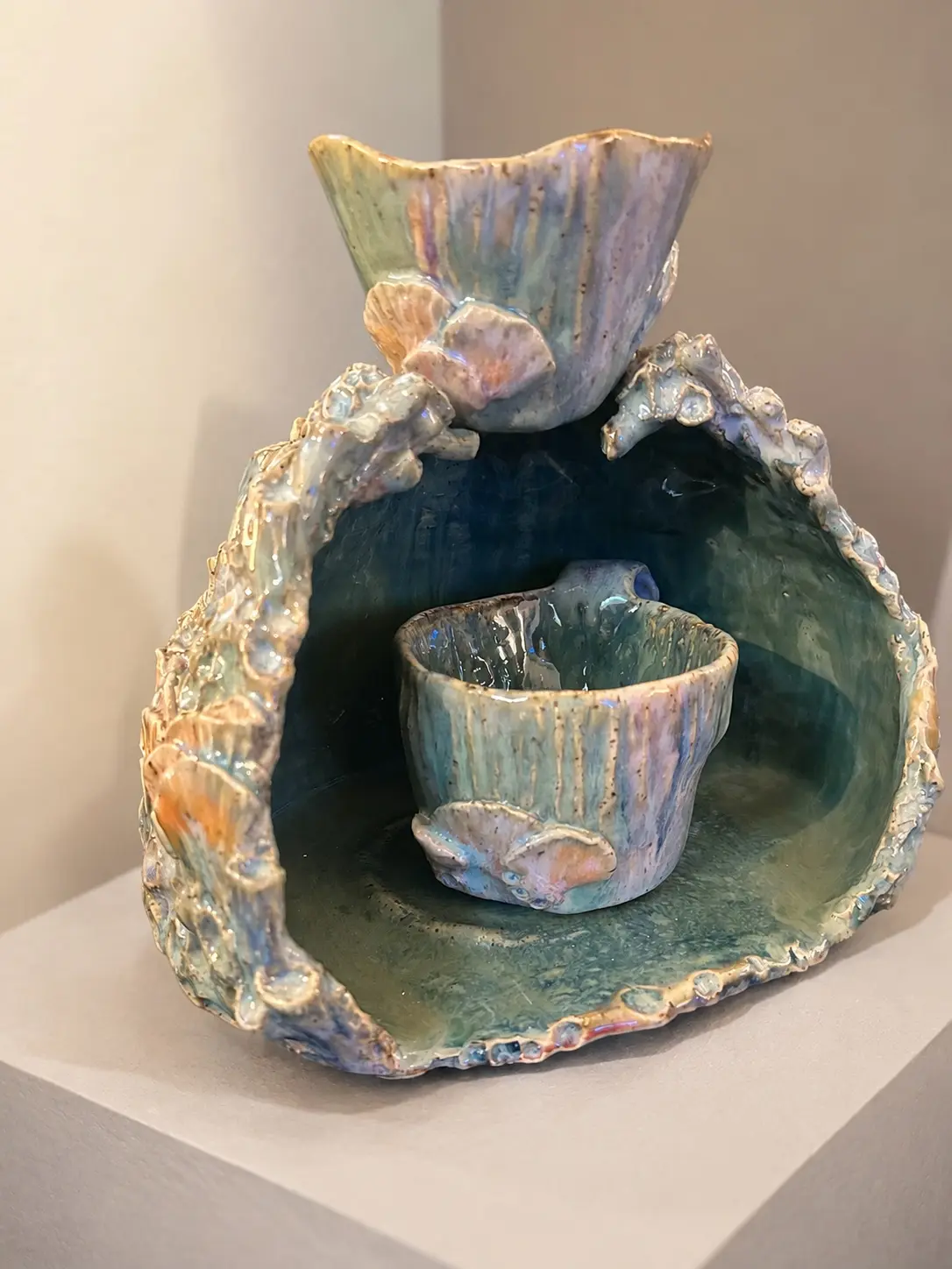 Organic ceramic grotto holding two shell-decorated cups